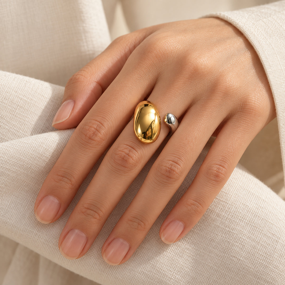 Nahaufnahme einer Hand mit offenem Bicolor-Ring aus Edelstahl und zwei unterschiedlich grossen Tropfenenden.